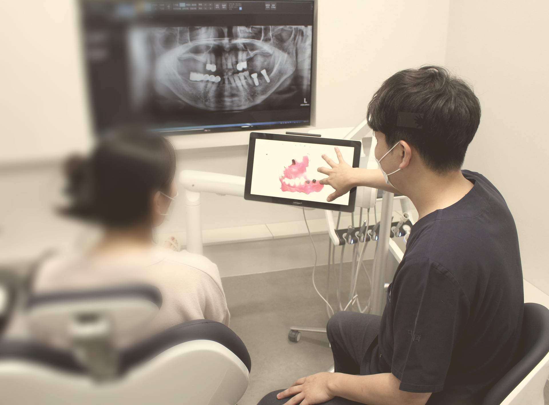 상담실에서 파노라마 엑스레이와 구강 사진을 보며 설명하는 장면